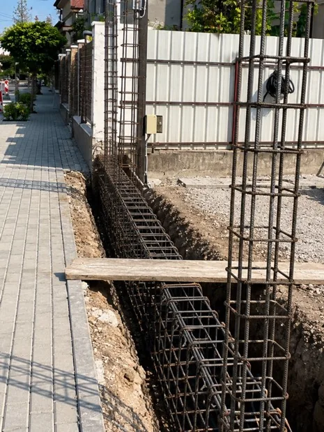 Fundație armată cu grindă și stâlpi din armătură montați în șanț, pe limita de proprietate