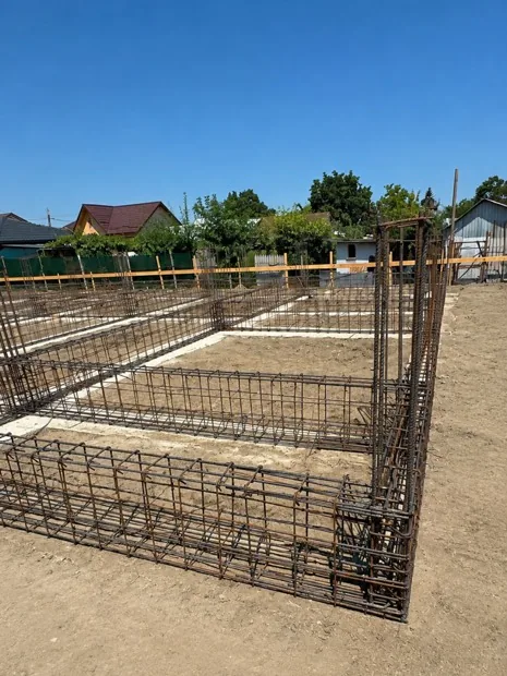 Fundație de casă cu carcase de armătură și tălpi armate, pregătită pentru turnarea betonului