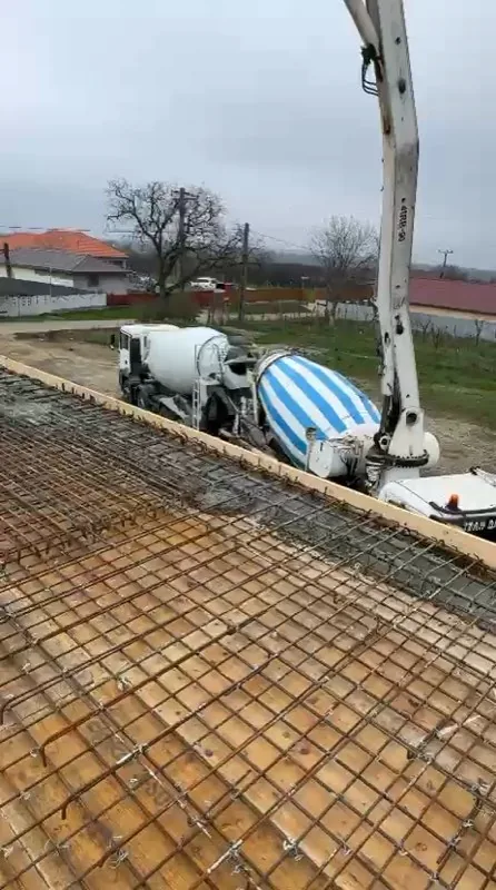 Filmare de pe șantier în timpul turnării unui planșeu de beton, cu pompă și autobetoniere